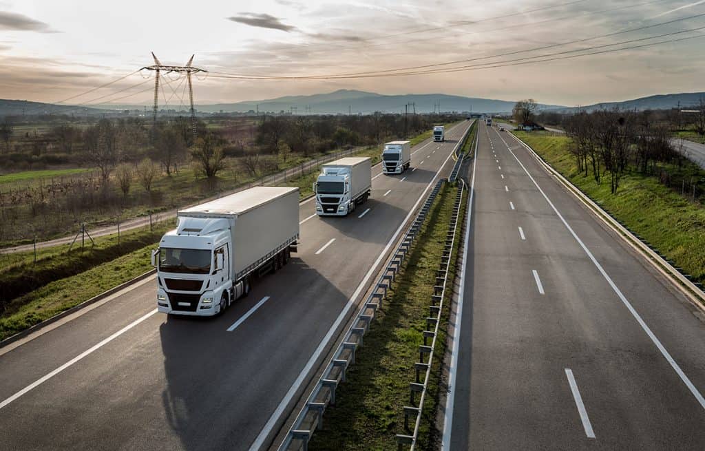 Caravana o convoy de camiones en línea en una carretera rural